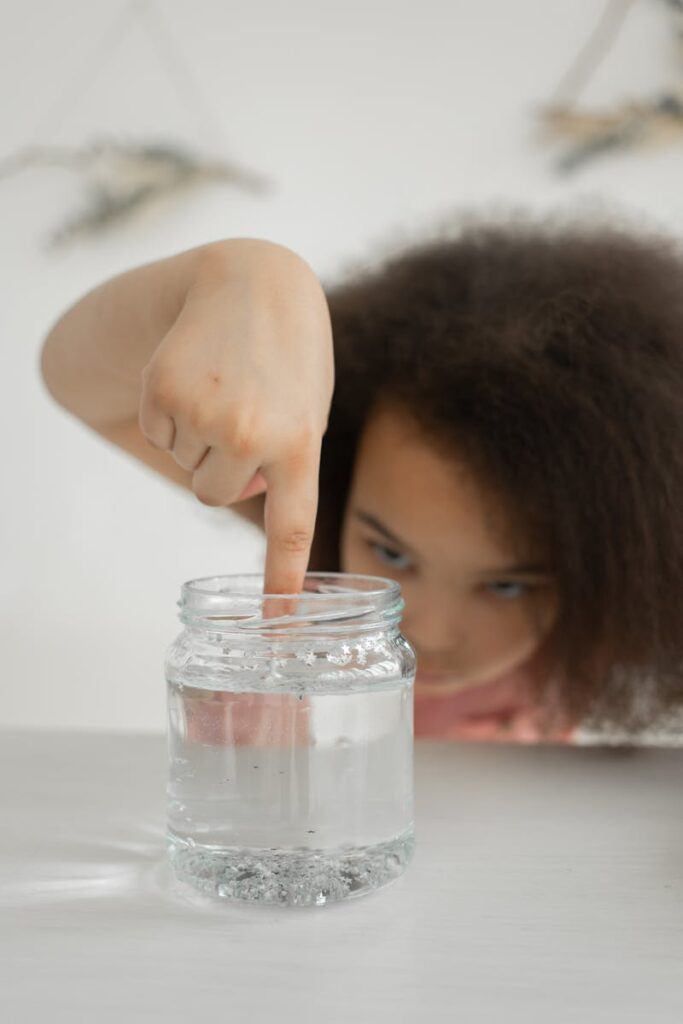 Concentrated black kid doing experiment with transparent slime